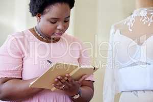 Getting the measurements. an attractive young seamstress writing notes while working in her boutique.