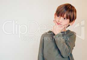 Shadows peeking in his eyes. Studio shot of a cute little boy lost in his thoughts while posing against a wall.