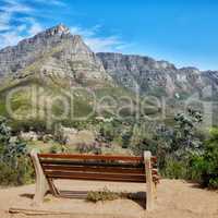 Wooden bench in a relaxing mountain range in a botanical garden. Table Mountain National park in Cape Town, South Africa with blue sky and local seating to enjoy calm and zen view of mother nature