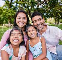 Portrait of happy asian family in the park. Family portrait of husband and wife sitting and enjoying free time with their daughters