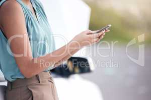 Closeup woman calling roadside assistance. Hands of a young woman dialling for help after a vehicle breakdown. Having car trouble and in need of a mechanic or tow truck. Stranded and alone on the road