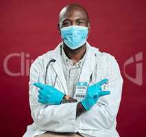 African american covid doctor holding corona vaccine and needle while wearing surgical face mask. Portrait of black physician holding drug vial and syringe against red studio background with copyspace
