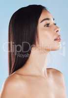 One beautiful young hispanic woman with healthy skin and sleek hair posing against a blue studio background. Mixed race model with flawless complexion and natural beauty