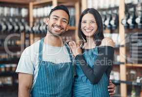 Portrait of a happy young hispanic man and woman working in a store or cafe. Friendly couple and coffeeshop owners managing a successful restaurant startup