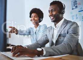 Happy african american male call centre telemarketing agent discussing plans with colleague while working together on computer in an office. Two consultants troubleshooting solution for customer service and sales support