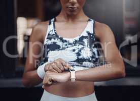 Closeup of one mixed race woman checking time on digital wristwatch with blank display screen while running outdoors. Female athlete wearing fitness tracker on arm to monitor progress, heart rate and calories burned during training exercise in the city