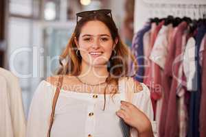 I love shopping here. an attractive young woman standing in a clothing store during her shopping spree.