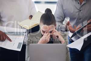 When things start feeling overwhelming, its time for a break. Shot of a young businesswoman suffering from a headache in a demanding work environment.