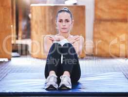 Building core strength and stability. Portrait of a sporty young woman doing sit ups while exercising in a gym.