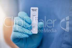 Unrecognizable doctor holding a rapid covid test while working at a hospital. One unrecognizable doctor wearing a glove and showing and holding a covid test while at work at a clinic