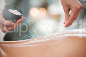 Smoother skin for a gentler experience. Shot of a masseuse pouring exfoliating salt scrub onto a clients back.