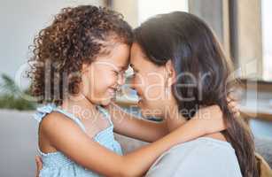 Close up of joyful mother and daughter sharing special moment while touching foreheads and sitting face to face at home. Sweet moment between parent and child showing love and affection