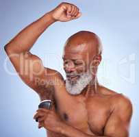 Smell young again. Studio shot of a mature man applying deodorant to his armpit against a blue background.