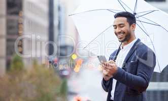 Getting insurance is as simple as sending a text. a handsome young businessman sending a text while standing outside with an umbrella in the city.