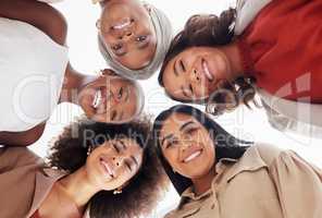 Low angle portrait of diverse group of businesswomen huddled together with heads in centre. Smiling ethnic team of professional colleagues feeling united, supported and empowered. Success in business