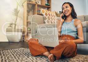 .Beautiful mixed race woman using blogging laptop and cellphone to talk to clients in home living room. Hispanic entrepreneur sitting cross legged alone on lounge floor and networking on technology