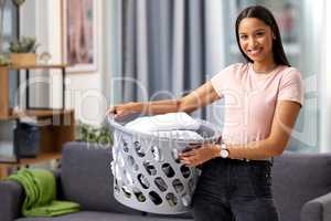 Time to pack these away. Cropped portrait of an attractive young woman carrying a basket of freshly washed and folded linen while spring cleaning at home.