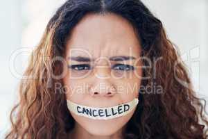 Cancel culture has become so common. Portrait of a young woman with tape on her mouth that has the word cancelled written on it.