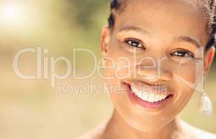 Closeup portrait of a beautiful young African American woman face. Smiling black female showing her healthy teeth and perfect dental and oral hygiene while outside in the city enjoying fresh air