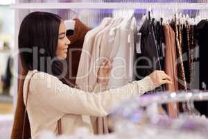 I love what I see. a young woman looking through a clothing rail in a store.