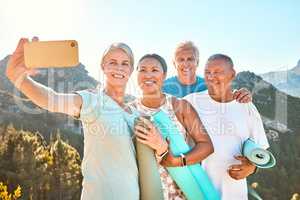 Group of active seniors posing together for a selfie or video call on a sunny day against a mountain view background. Happy diverse retirees taking photo after group yoga session. Living healthy and active lifestyles