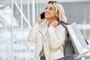 You have to see this dress. a young woman using her smartphone to make a phone call while shopping.