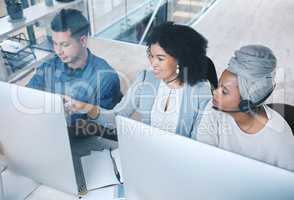 Mixed race female call centre telemarketing agent from above discussing plans with colleagues while working together on computer in an office. Group of diverse consultants troubleshooting solution for customer service and sales support