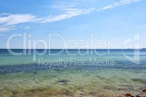 Calm sea shore on a blue horizon and rocky coastline. Panoramic landscape of tropical ocean on a summer day. Tranquil view of serene beach scene, holiday destination for travel and tourism