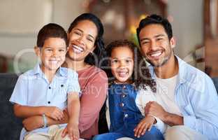 Portrait of a smiling couple with little kids at home. Mixed race mother and father bonding with their son and daughter on a weekend inside. Hispanic boy and girl enjoying free time with their parent