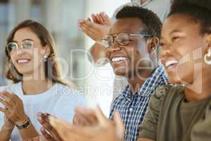 Group of joyful diverse businesspeople clapping hands in support during a meeting together at work. Happy african american businessman wearing glasses giving a coworker an applause in a workshop