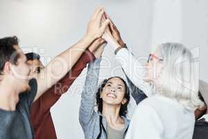 Diverse group of people standing together in circle and raising their hands in middle after therapy for a high five. Smiling support group celebrating successful session. Friends support mental health