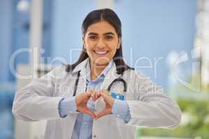Portrait of a happy mixed race female doctor forming a heart shape with hands at a hospital. Caring gp smiling and showing heart symbol to support charity. Healthcare professional working in cardiology