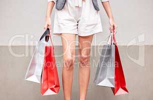 Ive been out bargain hunting today. an unrecognizable woman standing outside with shopping bags.