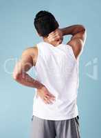 Rearview young mixed race man wearing a vest in studio isolated against a blue background. Unrecognizable male athlete suffering from back pain or ache. Hes picked up an injury during exercise