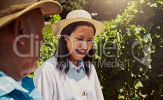 Smiling mixed race couple bonding on vineyard. Happy hispanic husband and wife laughing and enjoying day on a farm after wine tasting during a weekend. Man and woman wearing hats and standing together