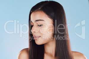 One beautiful young hispanic woman with healthy skin and sleek hair posing against a blue studio background. Mixed race model with flawless complexion and natural beauty