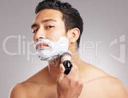 Handsome young mixed race man shirtless in studio isolated against a grey background. Hispanic male applying shaving cream foam to his face before a shave. Take care of your skin whenever you groom