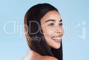 One beautiful young hispanic woman with healthy skin and sleek hair smiling against a blue studio background. Happy mixed race model with flawless complexion and natural beauty