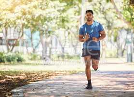 One active young indian man exercising outdoors. Handsome male athlete enjoying a jog or run for cardio training workout. Determined to build muscle and endurance for fitness and wellness goals