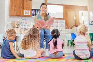 Everyone loves story time. Shot of a young woman reading to her preschool students.