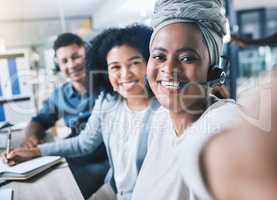 Portrait of happy african american call centre telemarketing agent taking selfies with diverse colleagues in an office. Confident and ambitious consultants determined to provide the best customer service and sales support