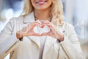 I have nothing but love for these purchases. a woman creating a heart shape with her hand while shopping.