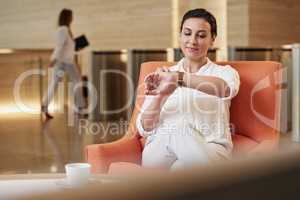Business woman checking her watch while sitting in airport waiting lounge for business travel. Business woman checking her watch while sitting in airport waiting lounge for business travel.