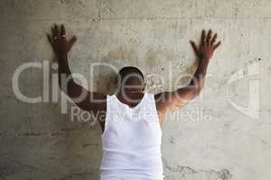 Hands up and spread em. Rearview shot of a man leaning against an urban wall with his hands up.