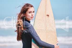 Portrait of a young caucasian female holding a surf board a the beach on vacation. Beautiful woman enjoying the weekend and staying fit and using her favourite hobby as an exercise