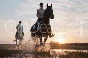 Sunset is our favourite time of the day to ride. Shot of two young women out horseback riding together.
