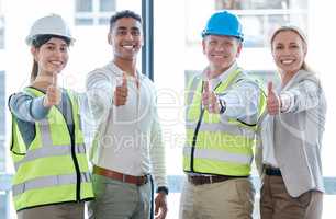 Backing the build. Cropped portrait of four construction workers giving thumbs up towards the camera.