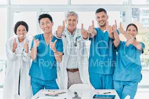 As confident as they are capable. Portrait of a group of medical practitioners showing thumbs up together in a medical office.