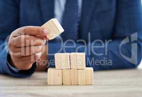 By failing to prepare, you are preparing to fail. Shot of an unrecognisable businessman working with wooden building blocks in a modern office.