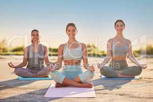 Full length yoga women meditating with legs crossed for outdoor practice in remote nature. Diverse group of mindful active friends bonding and balancing mental health. Young smiling serene zen people